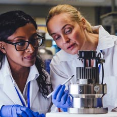 Two lab techs looking at a microscope