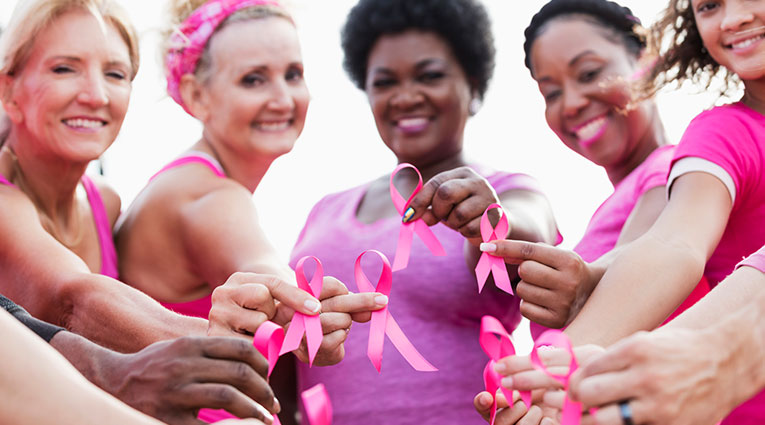 Women holding pink ribbons in recognition of breast cancer awareness month