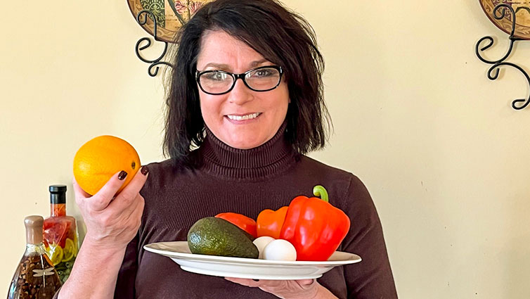 B-105 radio personality Chelsie holds an orange and a plate of vegetables