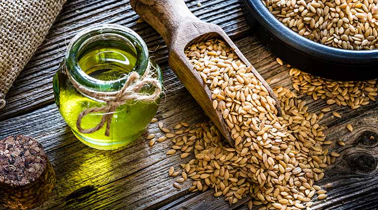 Flaxseed oil and whole flaxseed on a rustic table