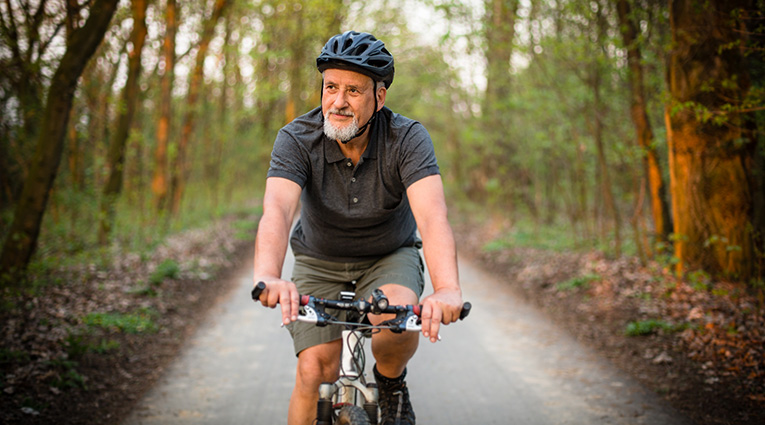 Man riding bicycle in tree lined grove