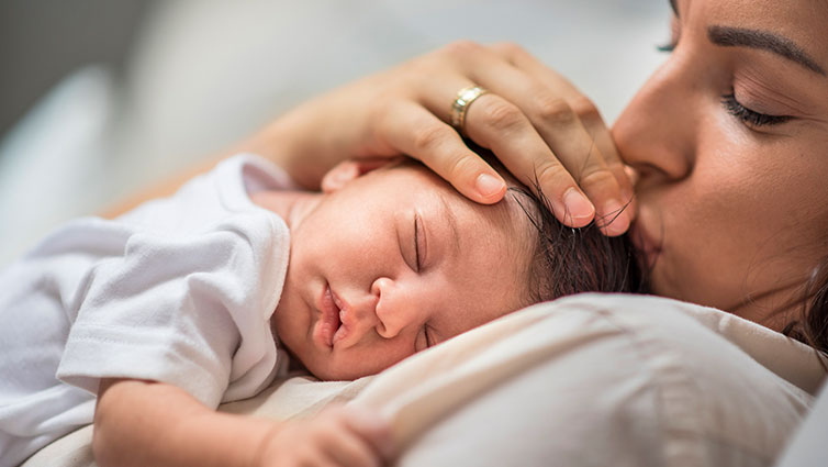 Sleepy baby rests on mother's chest