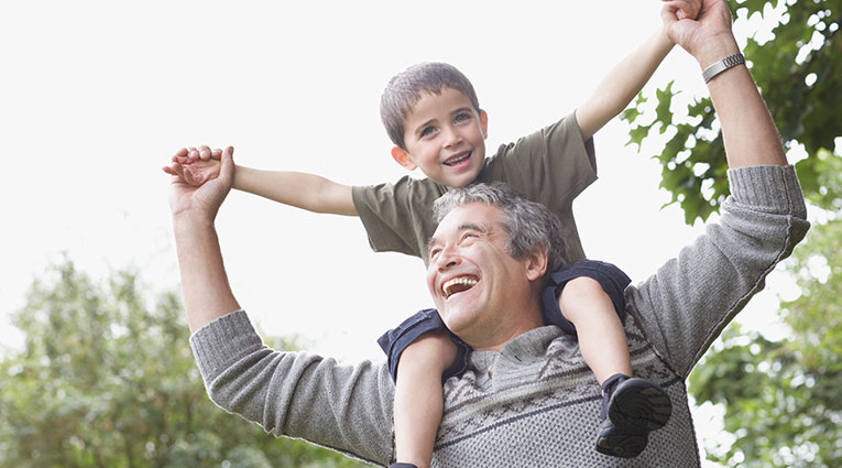 Man with grandchild on shoulders with arms outstretched