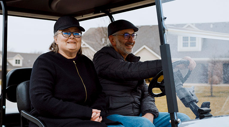 Terri and George Cecere ride their golf cart through their neighborhood