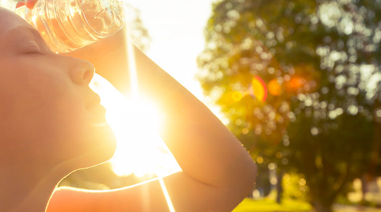 Woman with water bottle with hot sun in background