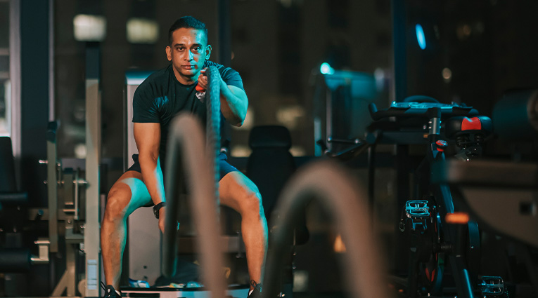 man in gym using battleropes