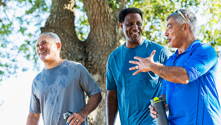 Three older men talking while walking outdoors