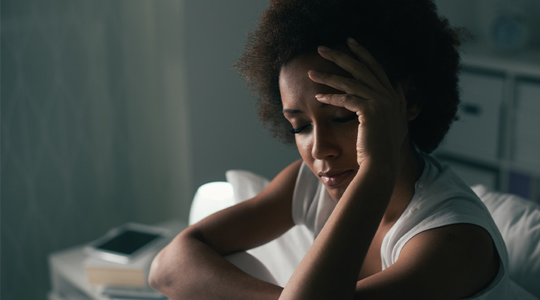 woman with migraine headache sitting in dark room