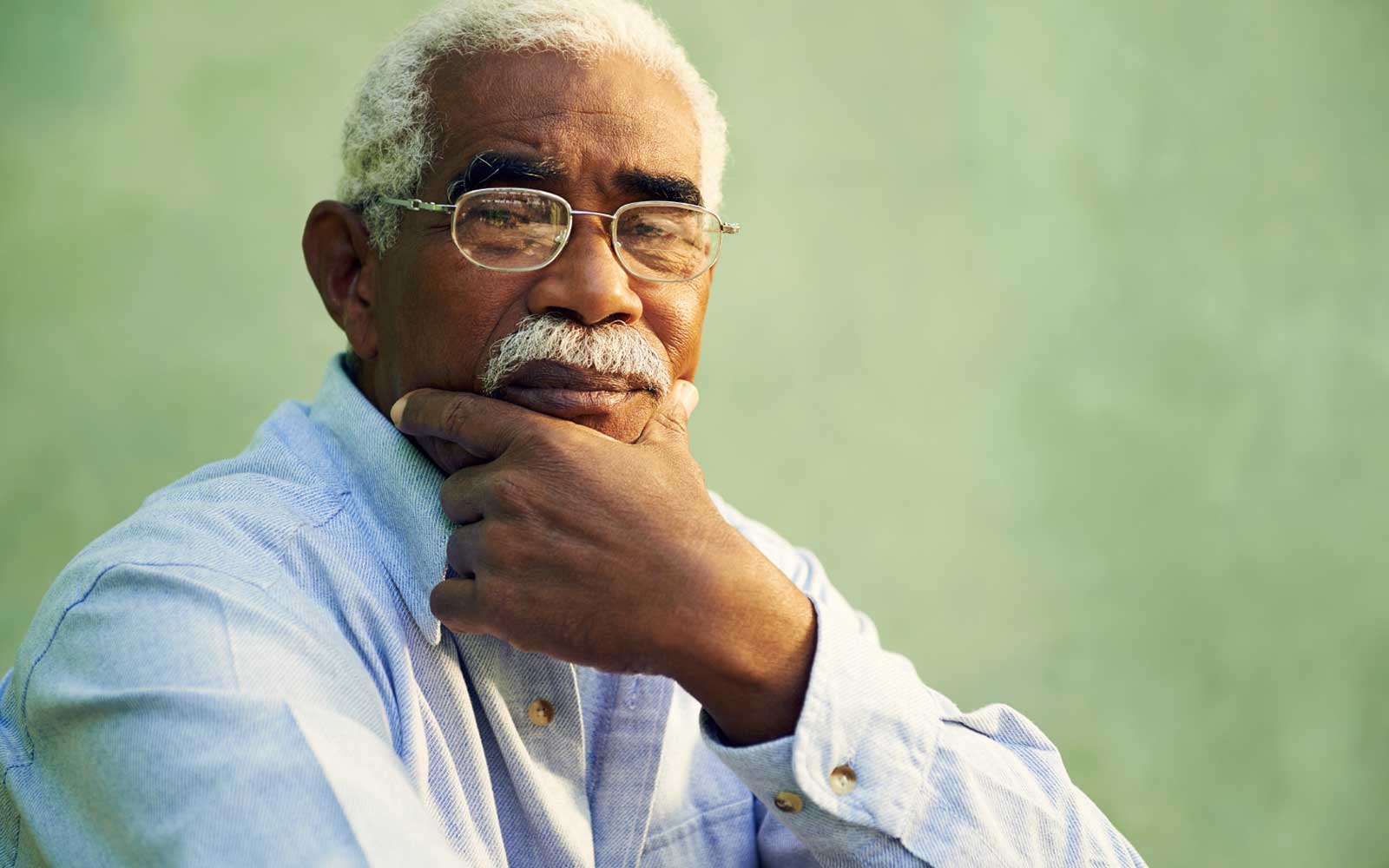 Senior African American man smiling and looking contemplative for a blog about dementia.