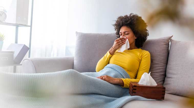 Woman sneezing into a tissue. 