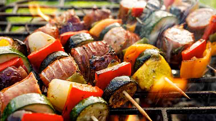 Skewers of colorful veggies on a grill for a blog about healthy cookouts.