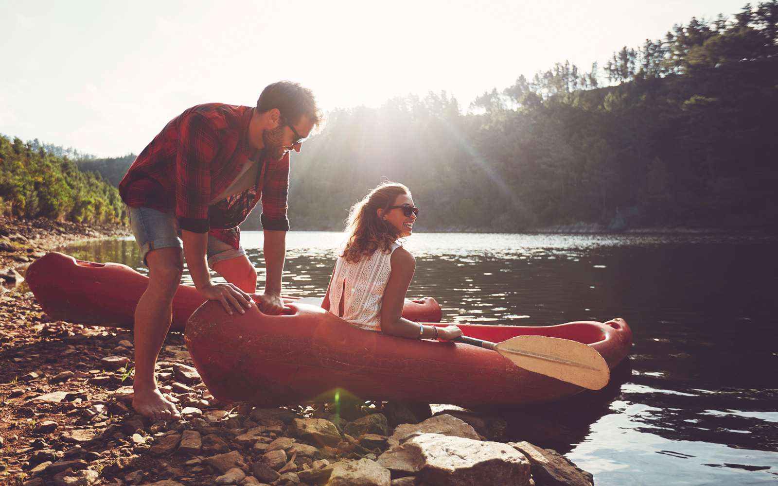 A man and woman in a canoe on the edge of water, practice water safety.