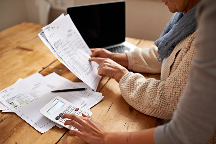 Person reviewing a bill on a computer and calculator