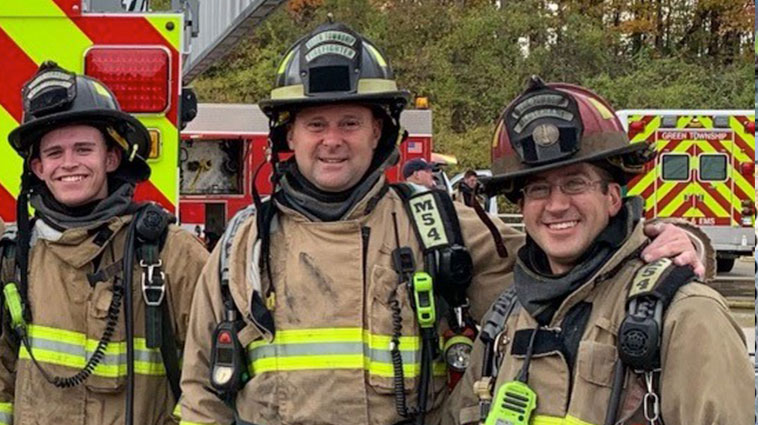 Firefighter Steve Alexander in full gear with two fellow firefighters.