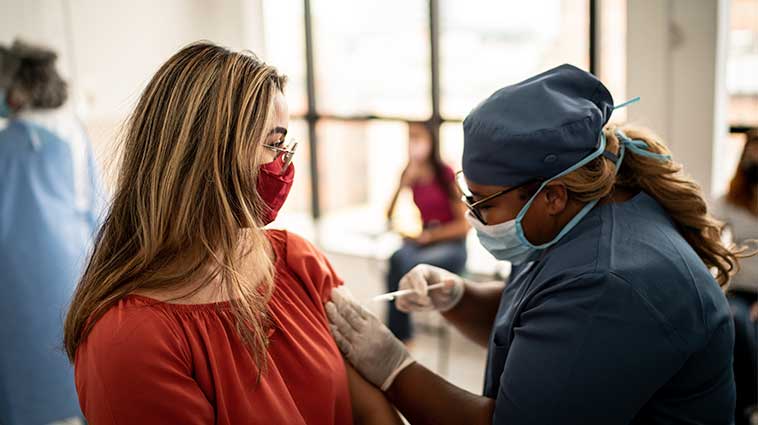 Young woman getting flu shot from female healthcare worker.