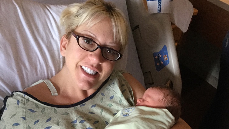 Q102 radio personality Jennifer Fritsch and her infant daughter in a hospital bed after birth.