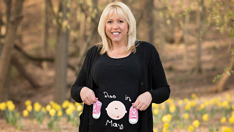 Q102 radio personality Jennifer Fritsch holding a sign announcing her pregnancy 4 years ago, for a blog about family planning.