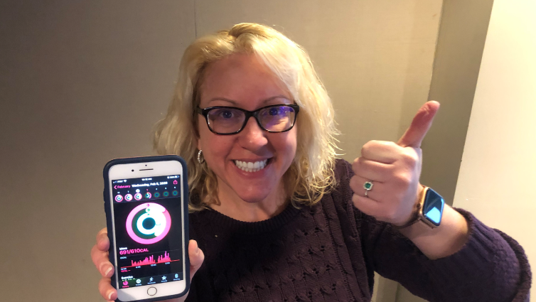 Q102 radio personality Jennifer Fritsch wearing a fitness tracker and showing the app on her phone