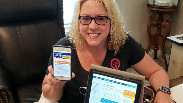 Q102 radio personality Jennifer Fritsch holding up a smartphone and tablet. 