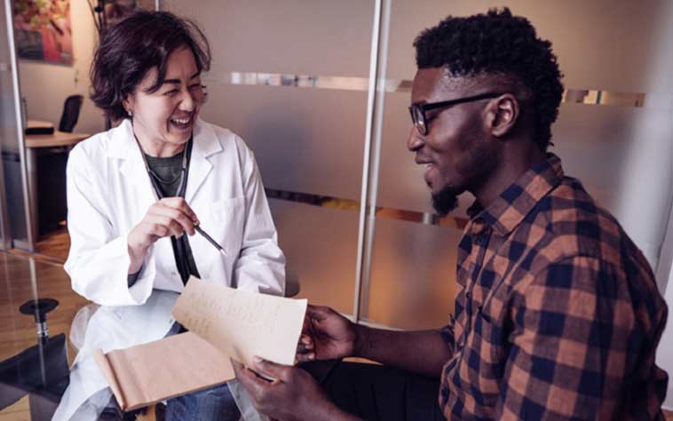 Asian female physician talking to African American male patient about men's health issues. 