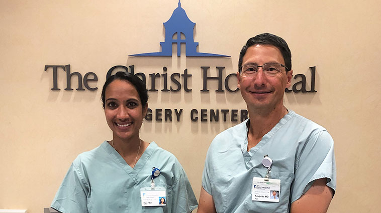 Orthopedic surgeons Allison Rao, MD, and Paul Favorito, MD, wearing scrubs and standing in front of The Christ Hospital sign.