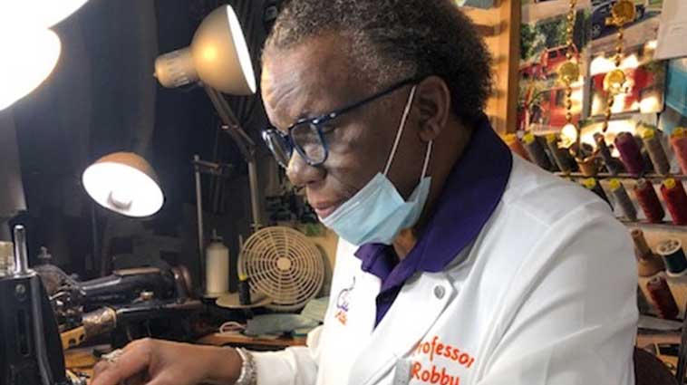 Tailor and prostate cancer survivor Robby Brookins works at a desk in his Finneytown, OH, shop.