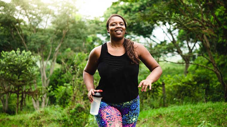 African American woman running in the woods, because running is good for your knees.