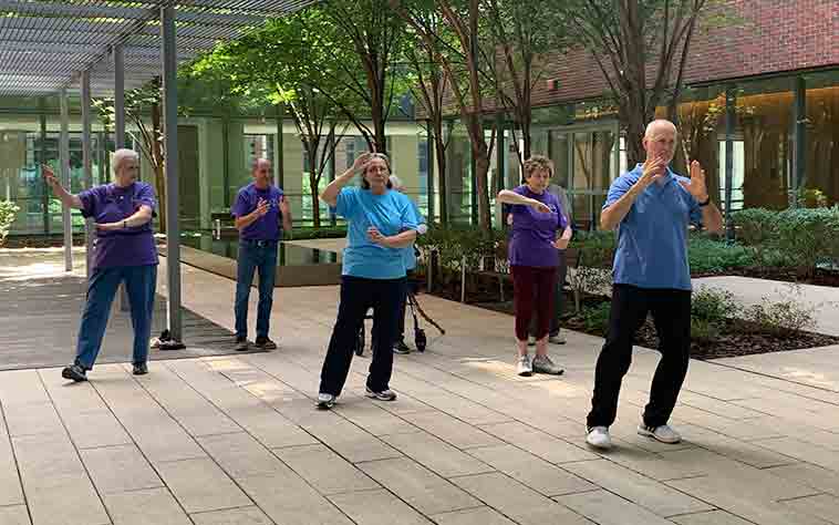 Tai Chi Instructor Ralph Dehner teaches tai chi class to participants in a garden patio at The Christ Hospital/