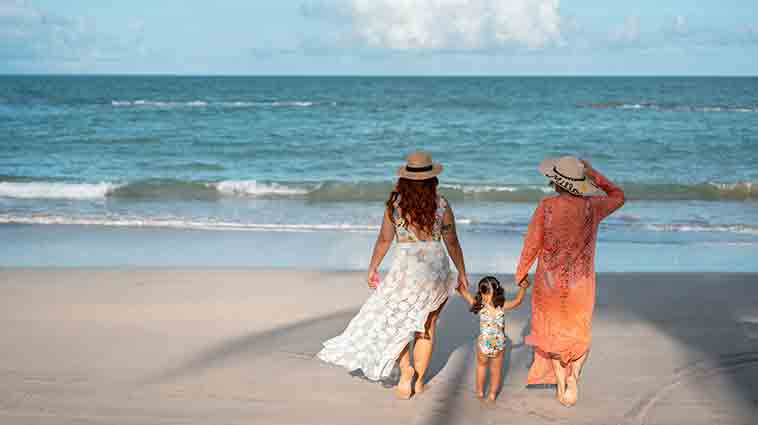 Two women and a young girl walk on the beach, after lung screening saved the one woman's life.