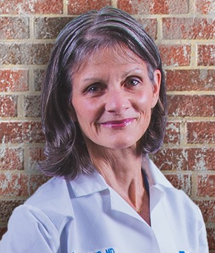Geraldine Vehr, MD, of The Christ Hospital Physicians - Primary Care, standing in front of a brick wall in a white lab coat.