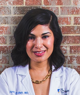 Aparna Shah, MD, standing on front of a brick wall