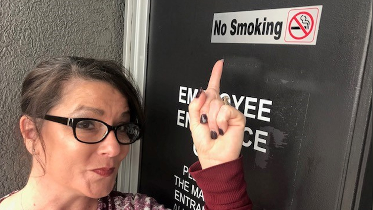 Chelsie from B105's Big Dave Show pointing to a No Smoking sign