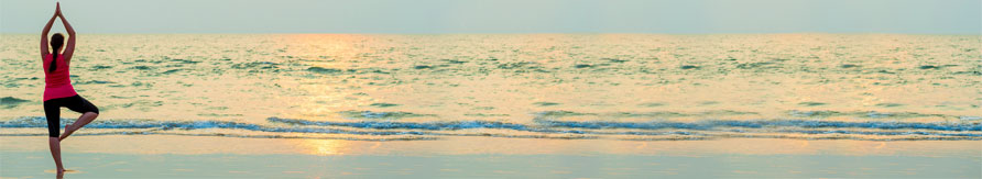 Woman in yoga pose on beach after gastrointestinal cancer treatment.