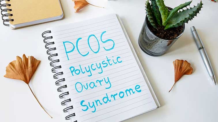 Notepad on desk with PCOS written on it.