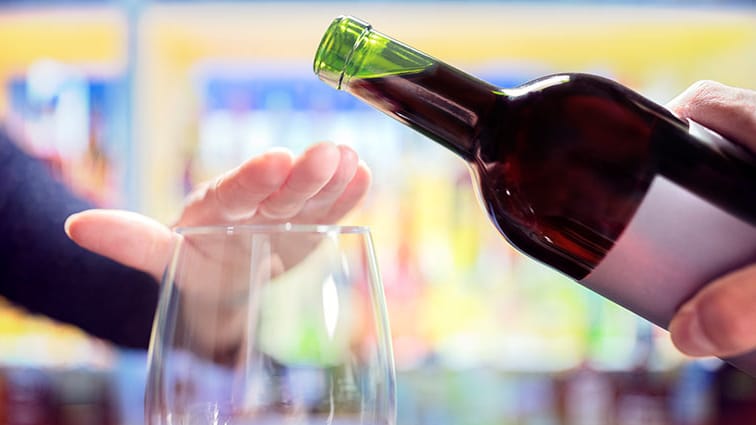 Hand stopping someone from pouring wine in glass