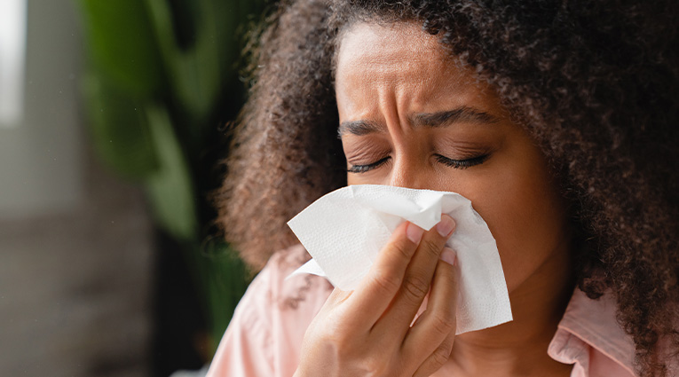 Woman with seasonal allergies uses tissue on nose