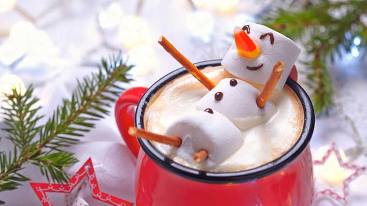 Marshmellow snowman floating in a cup of hot chocolate.