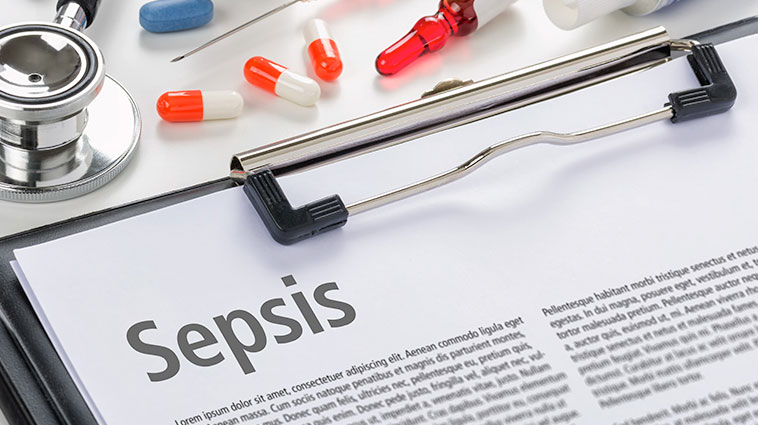 The word "sepsis" on a medical chart, amidst medication and a stethoscope.